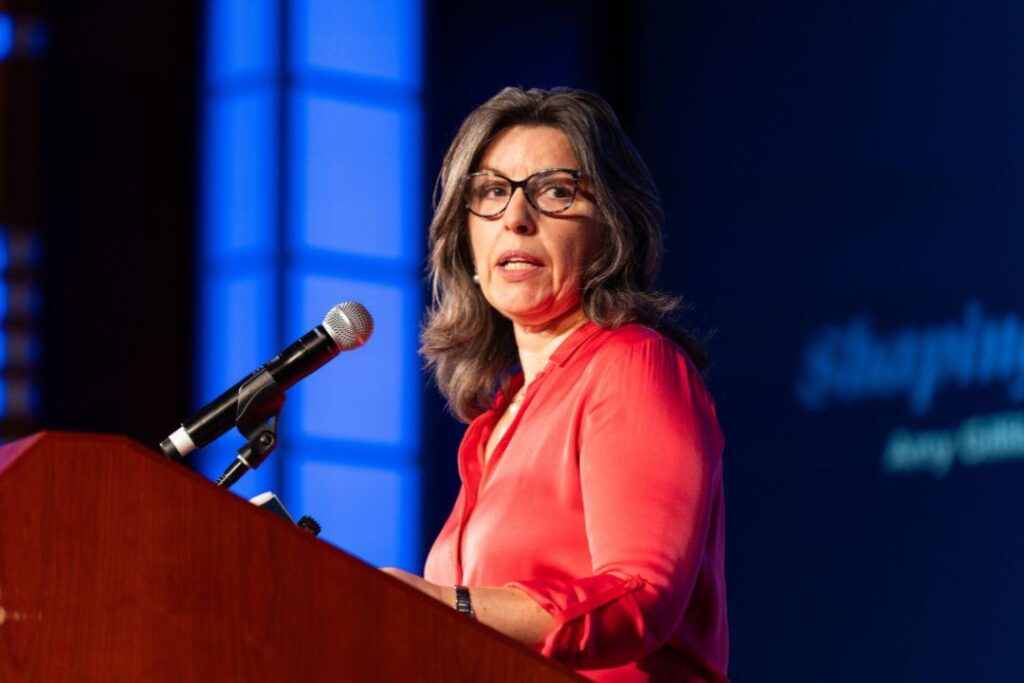 Lady in spectacles speaking in front of a lectern with microphone